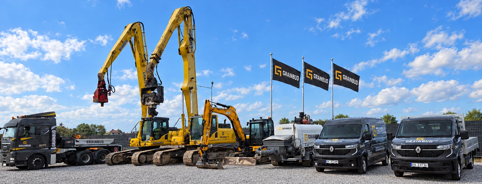 Flota GRAINBUD: ciągnik MAN, koparki Komatsu, koparka JCB, pompa do betonu i samochody Renault Master. Za sprzętem trzy flagi GRAINBUD.